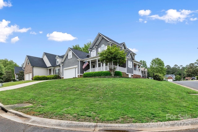 craftsman-style home with a front yard, driveway, an attached garage, and covered porch