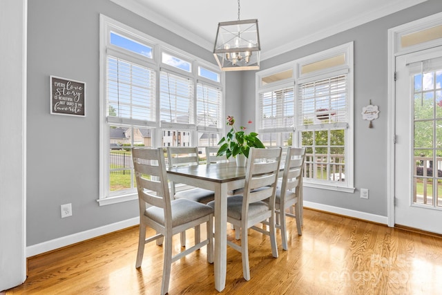 dining space with crown molding, light wood finished floors, a chandelier, and baseboards