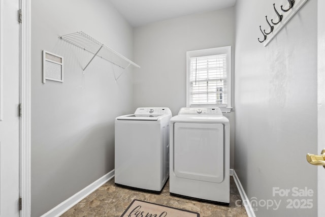 clothes washing area featuring baseboards, visible vents, washing machine and clothes dryer, and laundry area