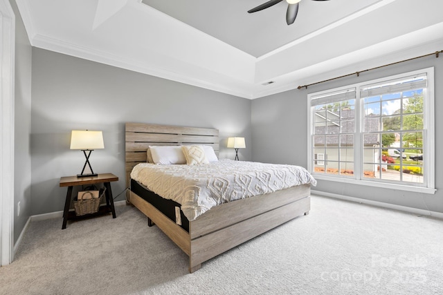 carpeted bedroom with ornamental molding, ceiling fan, a raised ceiling, and baseboards