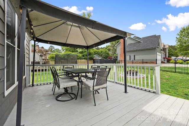 deck featuring a gazebo, outdoor dining space, a fenced backyard, and a yard