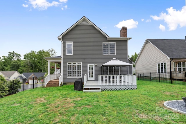 rear view of property featuring a deck, a gazebo, a chimney, a yard, and a fenced backyard