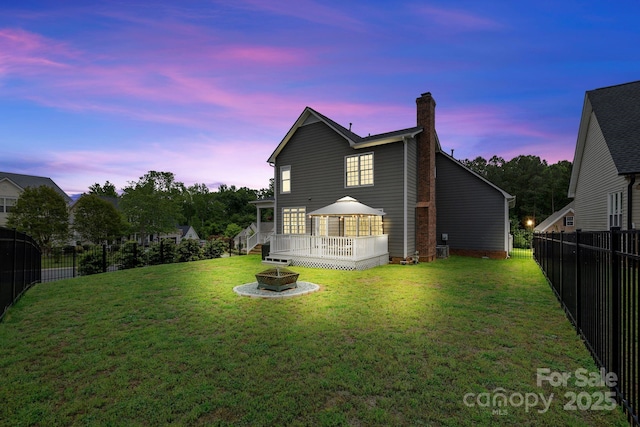 rear view of house with a chimney, an outdoor fire pit, a gazebo, and a yard