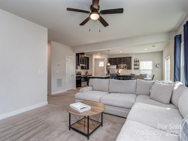 living area with visible vents, a ceiling fan, baseboards, and light colored carpet