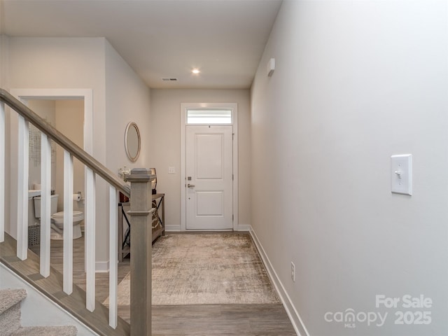 doorway to outside with baseboards, wood finished floors, visible vents, and stairs