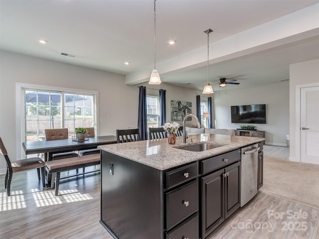 kitchen featuring stainless steel dishwasher, a sink, a center island with sink, open floor plan, and visible vents