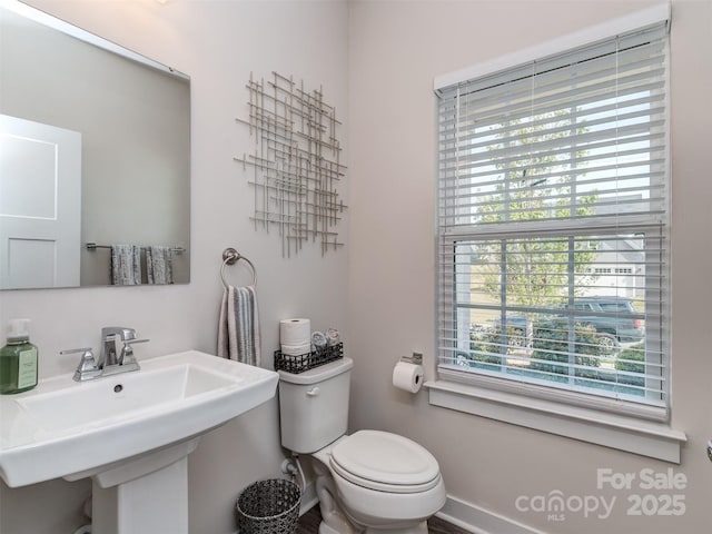 bathroom featuring baseboards, toilet, and a sink
