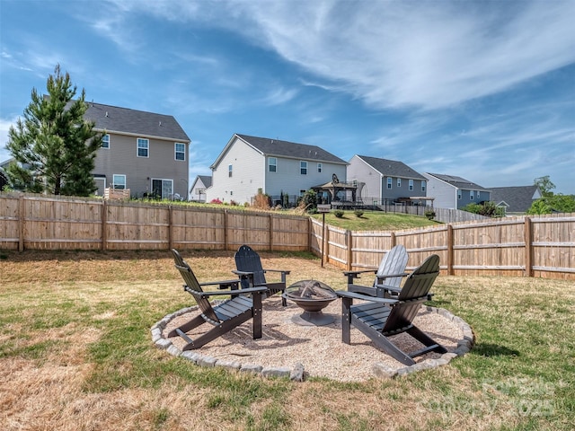 view of yard featuring a residential view, a fenced backyard, and an outdoor fire pit