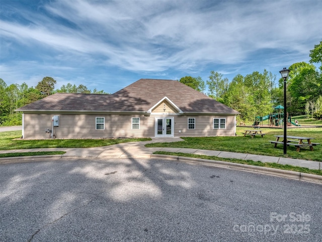 view of front of property featuring french doors, a front yard, and a playground