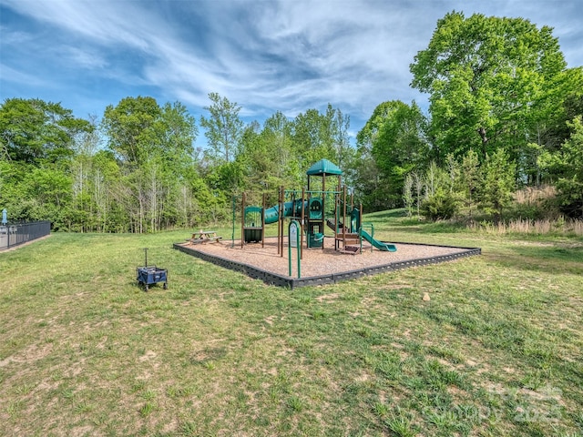 communal playground featuring a lawn and fence