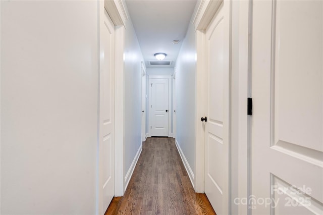 hall featuring baseboards, visible vents, and dark wood finished floors