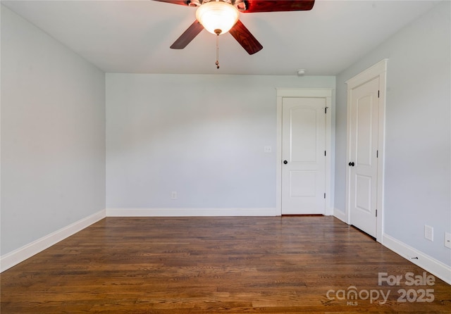 spare room with wood finished floors, a ceiling fan, and baseboards