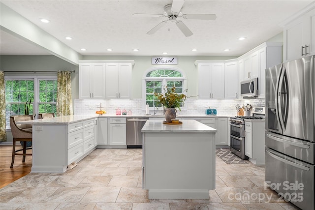 148 Broyles Rd, Hendersonville, NC 28791 - kitchen with stainless steel appliances, a peninsula, decorative backsplash, light stone counters, and recessed lighting