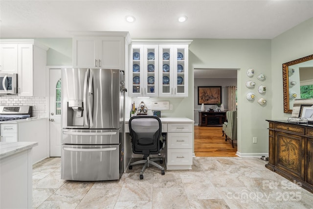 148 Broyles Rd, Hendersonville, NC 28791 - kitchen with stainless steel appliances, white cabinetry, glass insert cabinets, a desk, and backsplash