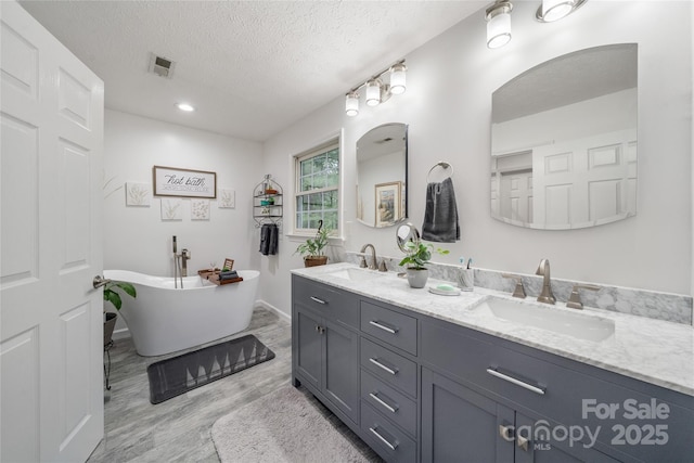 148 Broyles Rd, Hendersonville, NC 28791 - bathroom with double vanity, a freestanding tub, wood finished floors, a textured ceiling, and baseboards