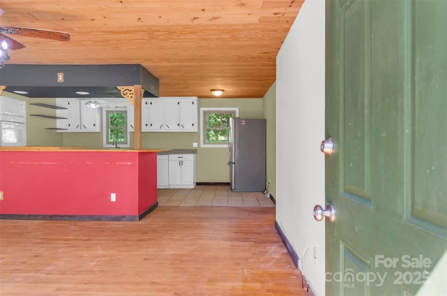 kitchen with freestanding refrigerator, oven, light wood-type flooring, white cabinets, and wooden ceiling