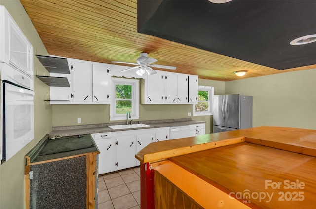 kitchen with white appliances, white cabinetry, a sink, light tile patterned floors, and exhaust hood