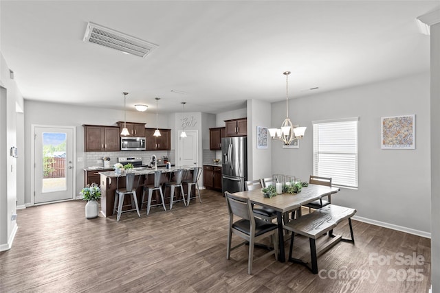 dining room featuring dark wood-type flooring, baseboards, and a chandelier