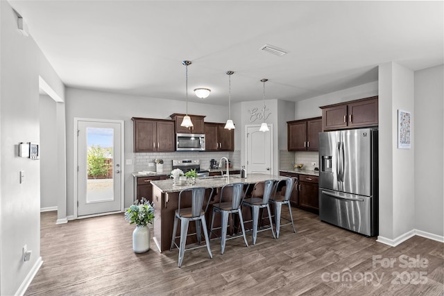 kitchen with appliances with stainless steel finishes, dark wood finished floors, baseboards, and tasteful backsplash