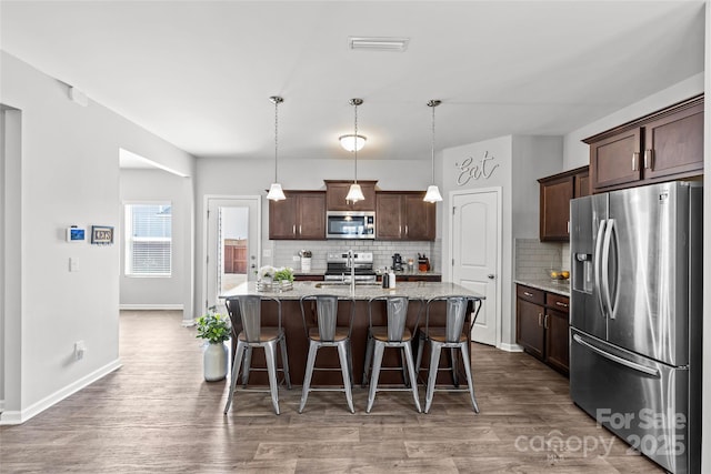 kitchen featuring stainless steel appliances, tasteful backsplash, a breakfast bar area, and dark brown cabinets