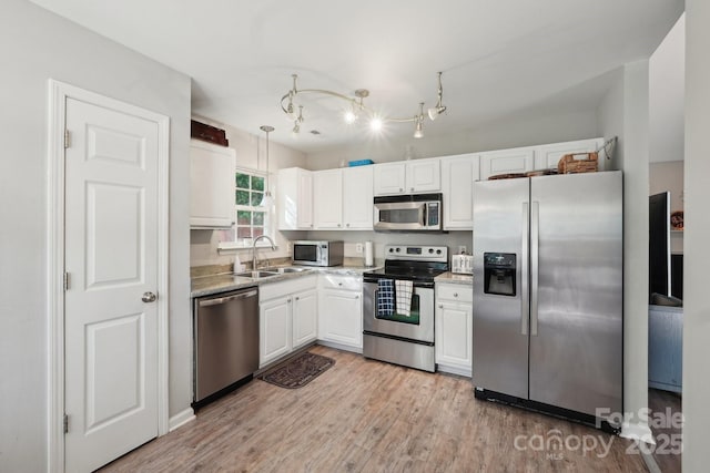 9200 Forest Green Dr, Charlotte, NC 28227 - kitchen with white cabinetry, stainless steel appliances, light wood finished floors, and a sink