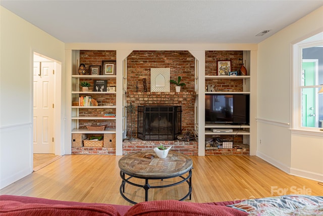 living area featuring a fireplace, wood finished floors, built in shelves, and baseboards