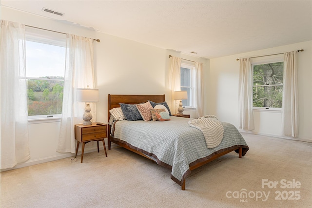 bedroom featuring visible vents and light colored carpet