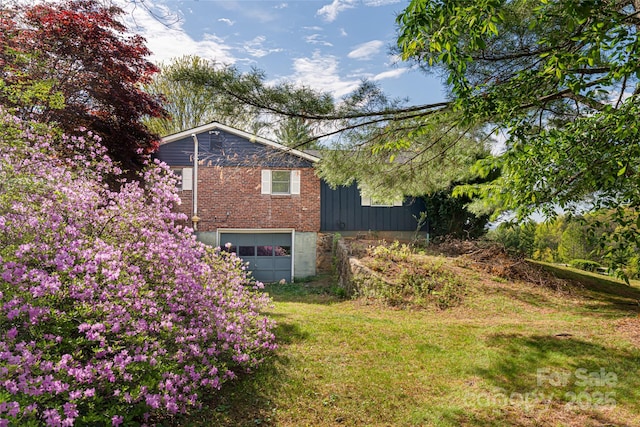 view of side of property featuring a garage, a yard, and brick siding