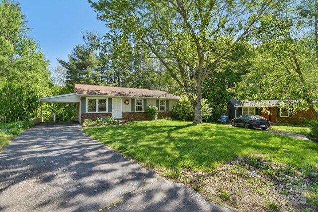 single story home featuring brick siding, driveway, a front yard, and an attached carport