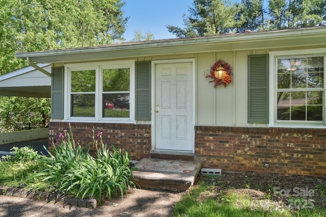 doorway to property with board and batten siding and brick siding
