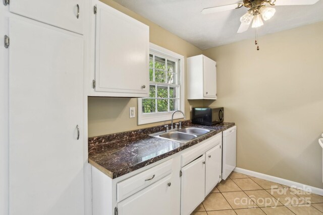 kitchen featuring white cabinetry, dark countertops, black microwave, and a sink