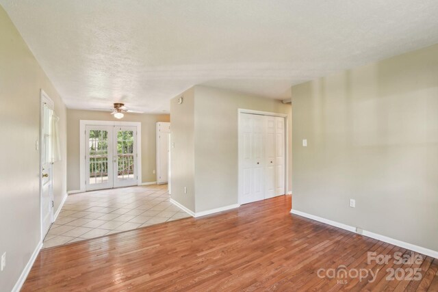 unfurnished room with a ceiling fan, baseboards, and light wood-style floors