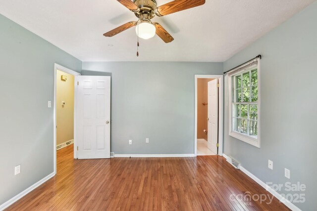 unfurnished bedroom featuring wood-type flooring, baseboards, visible vents, and ceiling fan