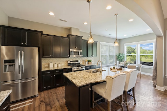 505 Chamberlain Ct, Mcadenville, NC 28101 - kitchen with an island with sink, arched walkways, a sink, backsplash, and stainless steel appliances