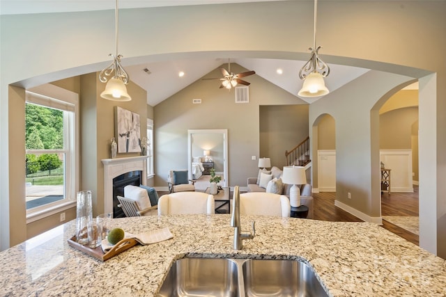 505 Chamberlain Ct, Mcadenville, NC 28101 - kitchen with light stone counters, a fireplace, arched walkways, open floor plan, and wood finished floors