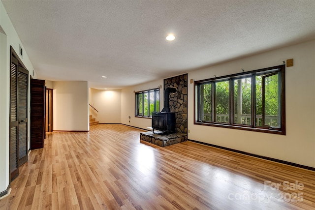 362 Cowan Valley Ests, Sylva, NC 28779 - unfurnished living room with a wood stove, a textured ceiling, stairway, baseboards, and light wood-type flooring