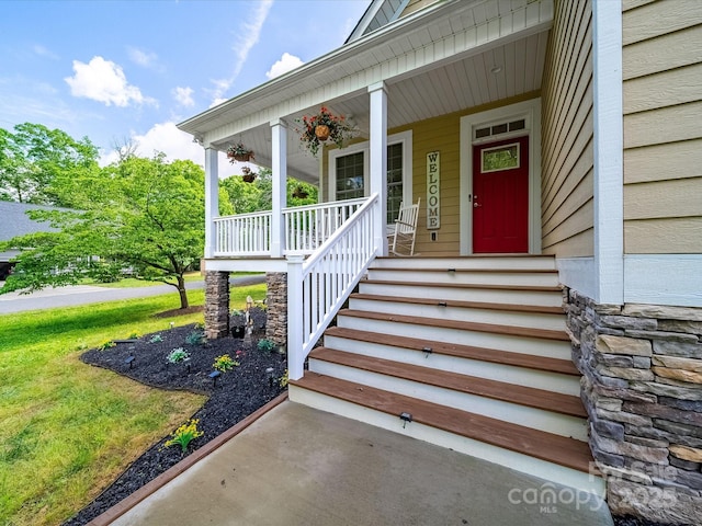 view of exterior entry with covered porch and stone siding