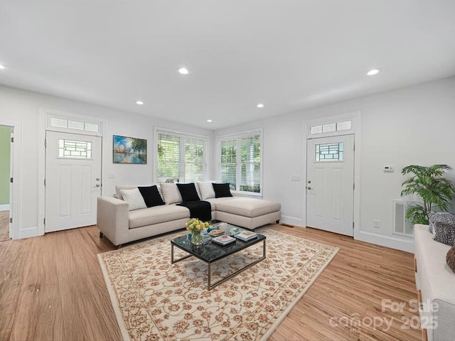 living area with light wood finished floors, plenty of natural light, baseboards, and recessed lighting