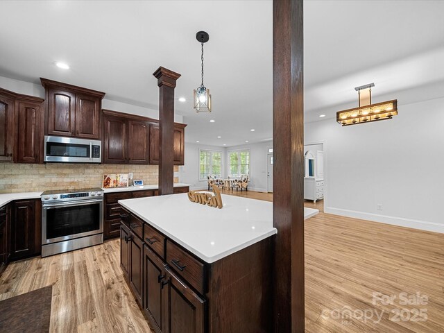 kitchen featuring appliances with stainless steel finishes, light wood finished floors, light countertops, decorative columns, and recessed lighting