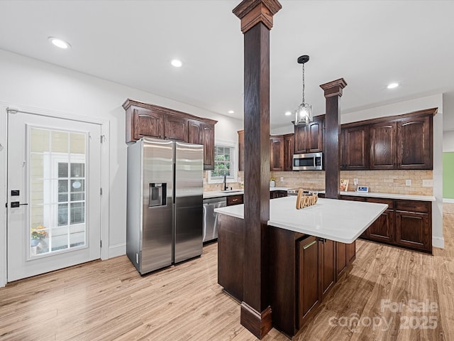 kitchen with appliances with stainless steel finishes, dark brown cabinets, light countertops, a sink, and light wood-style floors