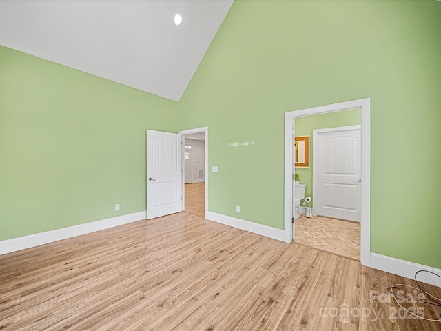 unfurnished bedroom featuring high vaulted ceiling, wood finished floors, and baseboards