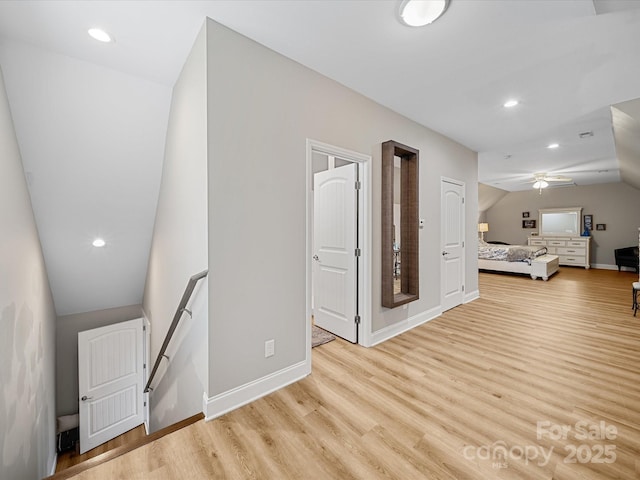 corridor featuring lofted ceiling, light wood-type flooring, baseboards, an upstairs landing, and recessed lighting