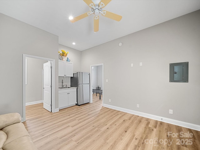 living room featuring electric panel, light wood finished floors, baseboards, ceiling fan, and recessed lighting