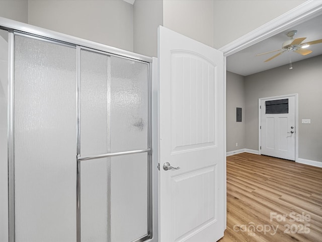 bathroom featuring wood finished floors, a ceiling fan, a shower stall, and baseboards