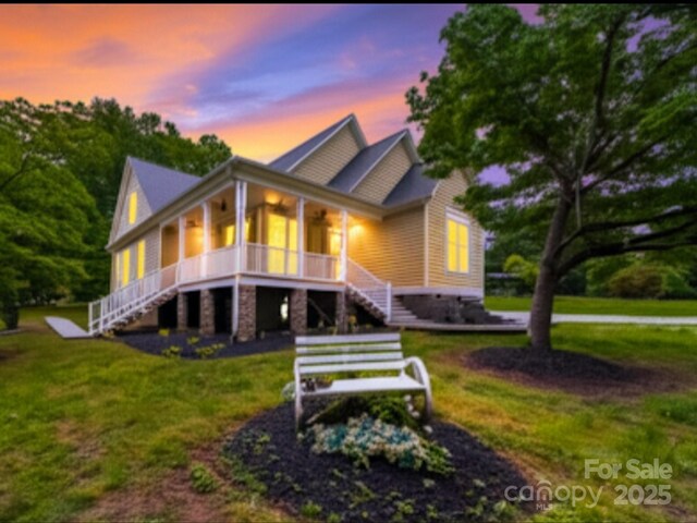 view of front facade with stairs, a lawn, and covered porch