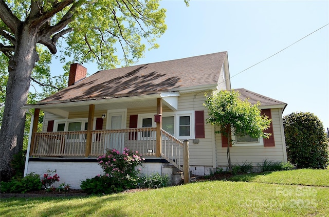 view of front facade featuring a porch, a front lawn, roof with shingles, and a chimney
