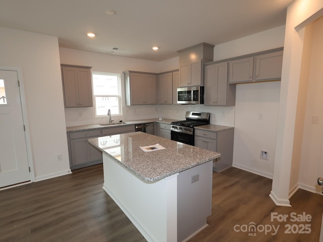 1119 Overbrook Pl, Wingate, NC 28174 - kitchen with gray cabinets, stainless steel appliances, a sink, a center island, and light stone countertops