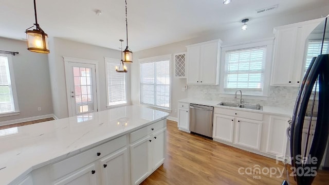 kitchen with decorative backsplash, dishwasher, a sink, freestanding refrigerator, and light wood finished floors