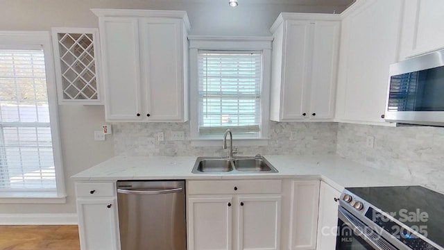 kitchen featuring white cabinets, stainless steel appliances, a sink, and tasteful backsplash