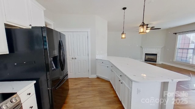 kitchen with light wood-style floors, a ceiling fan, a peninsula, and black fridge
